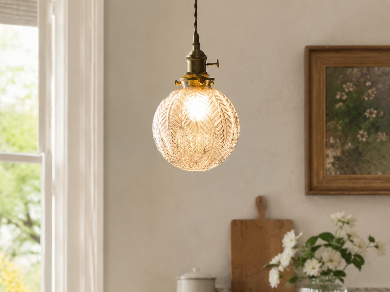 clear glass brass pendant light installed above a small dining table
