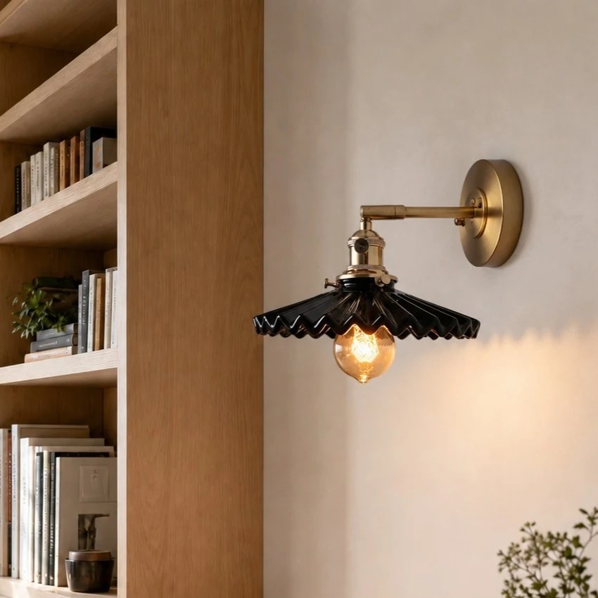 Black pleated ceramic wall sconce installed near shelving