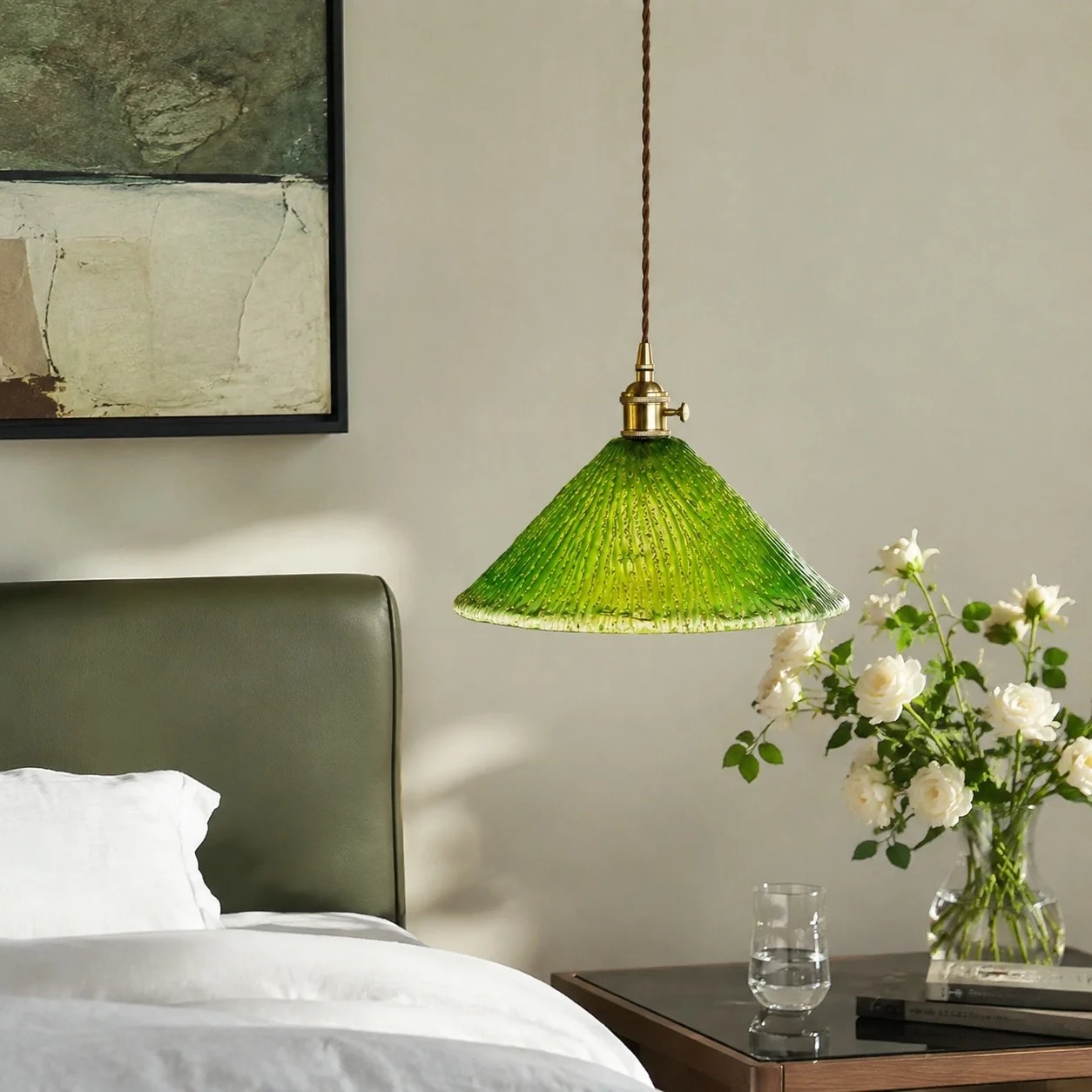 Green pendant light beside a bed