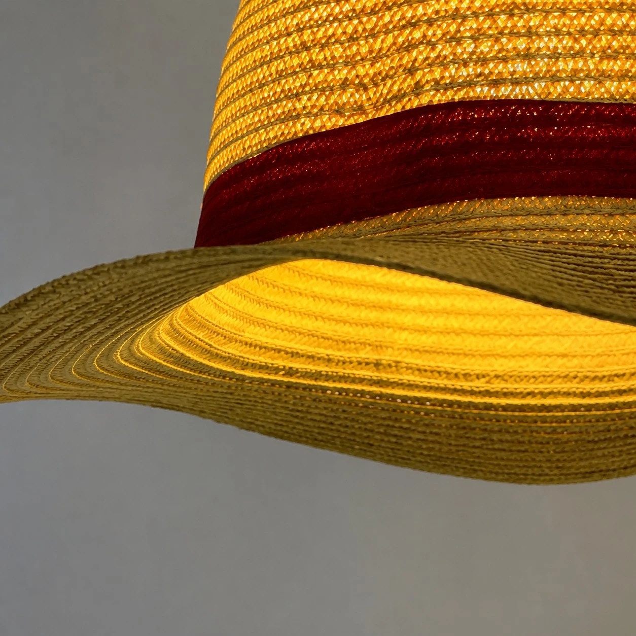 Layered straw texture, wide brim and a clean red accent band.