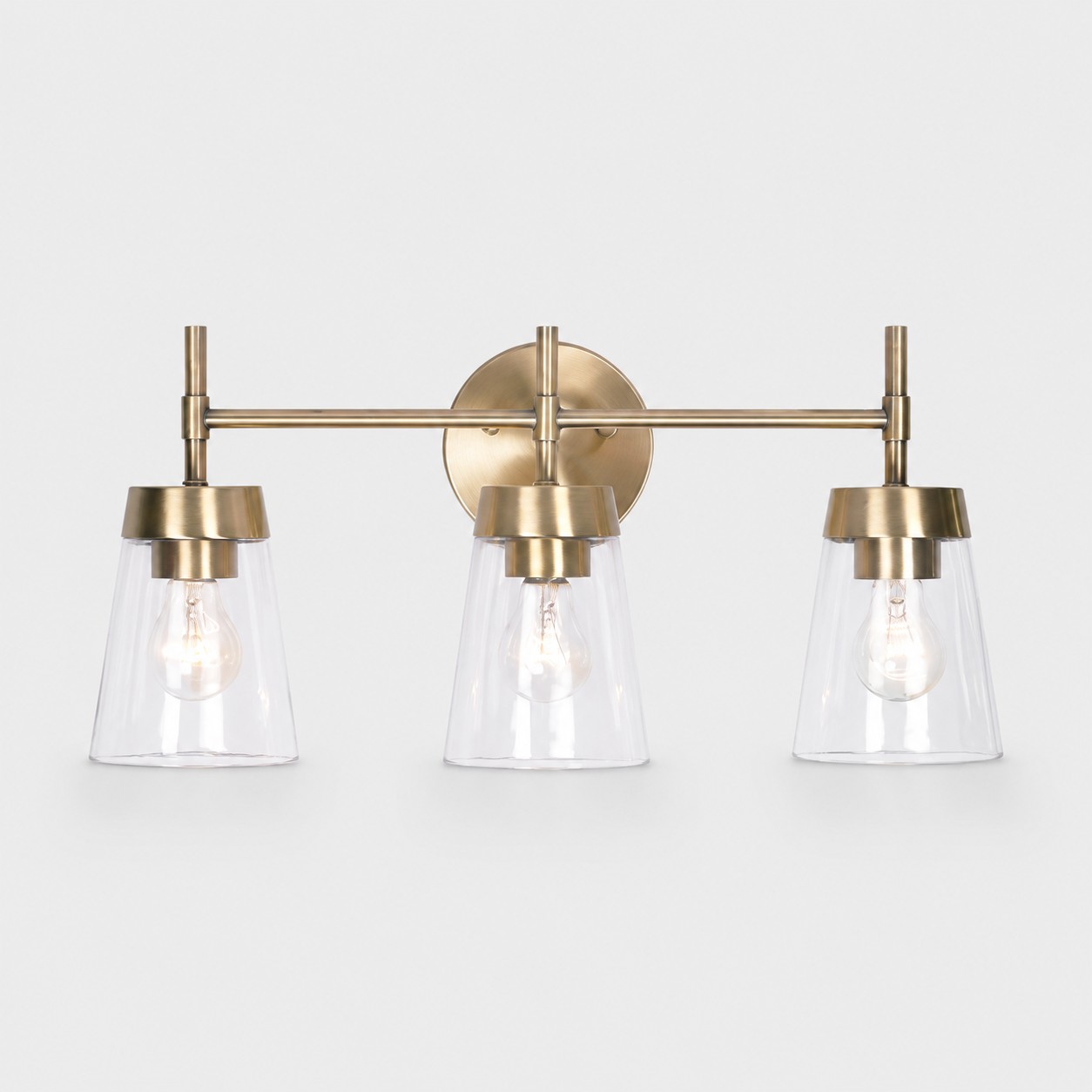 Wandlamp met drie lichtpunten van geborsteld messing op een witte achtergrond.