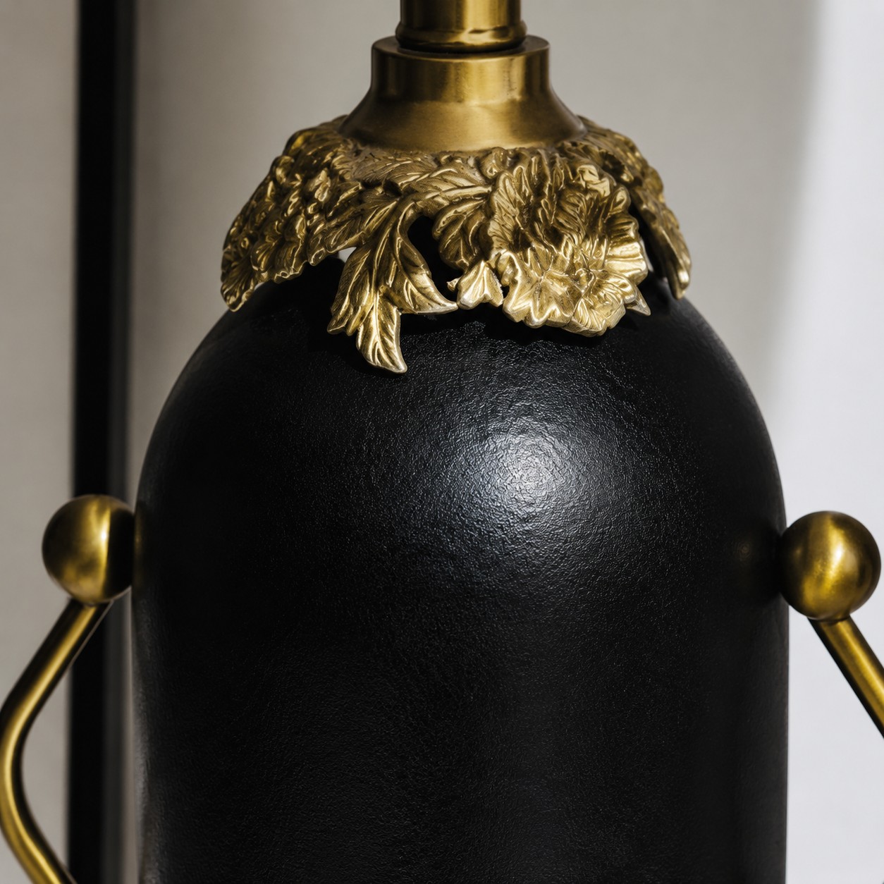 Close-up of matte black lamp body and brass-toned floral detail