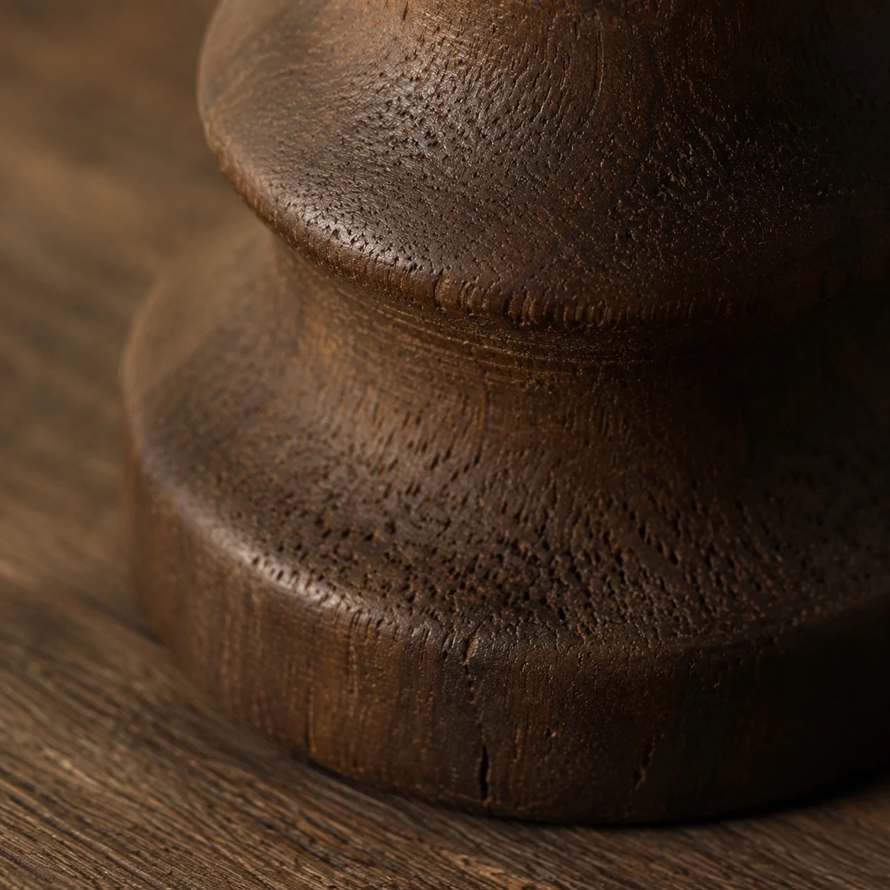 Detailweergave van de donker gecarboniseerde houten voet en de gedraaide contour.