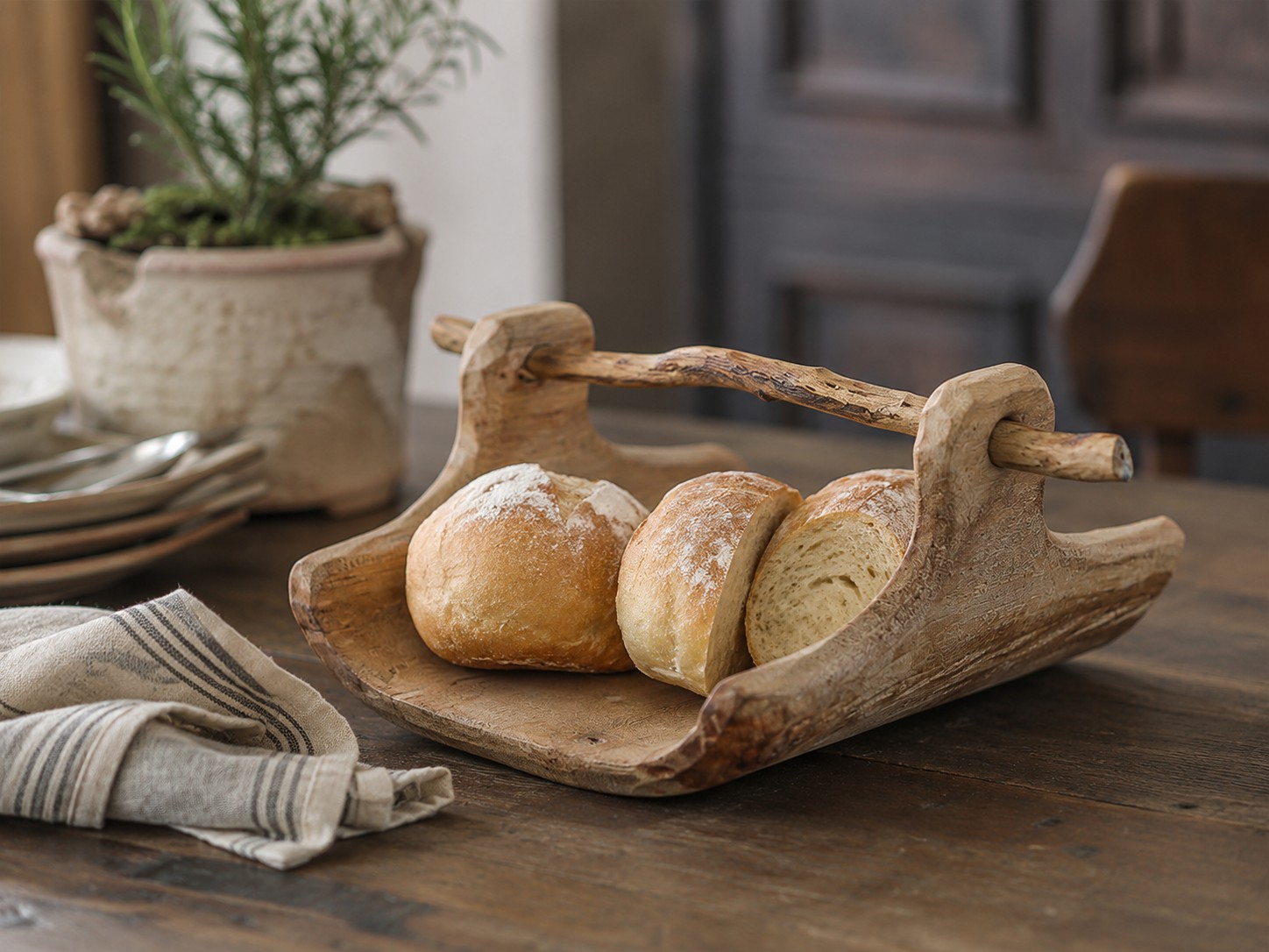 Plateau en bois de saule contenant du pain sur une table à manger rustique