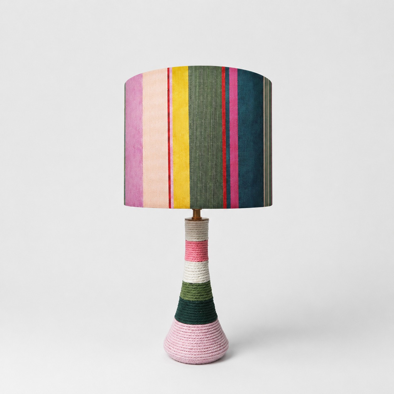 Lampe de table en tissu rayé coloré avec base recouverte de fil sur fond blanc