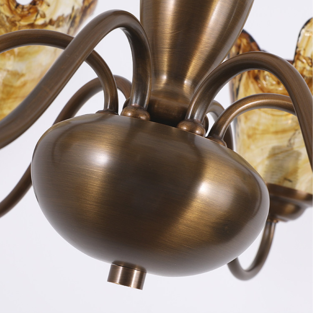 Curved chandelier arms connected to a rounded brass hub
