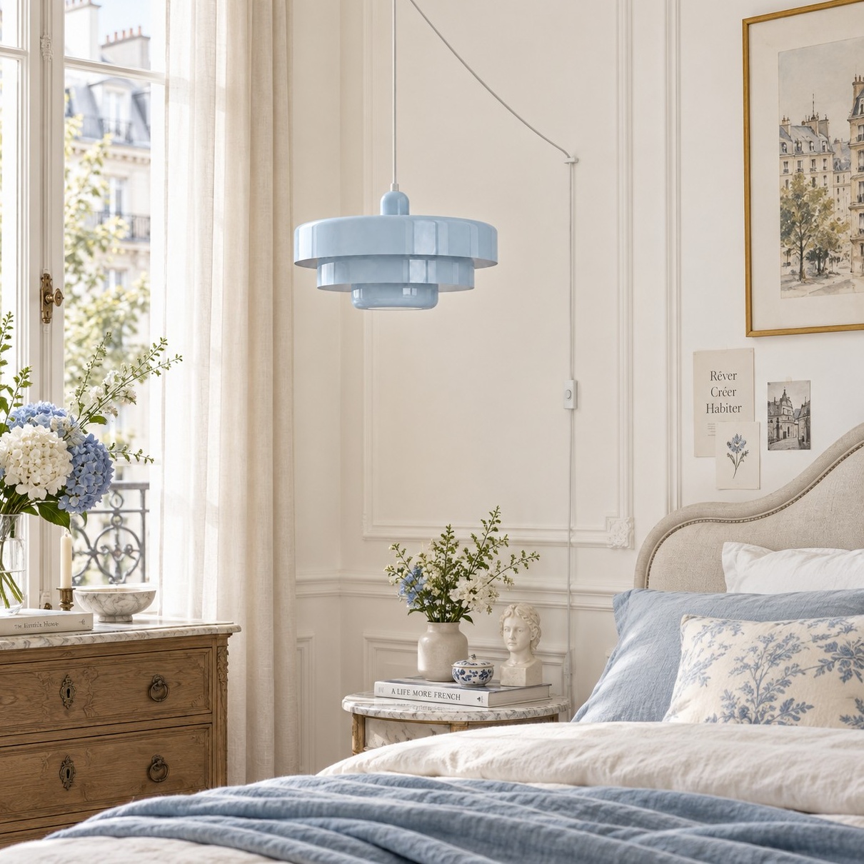 Lámpara colgante azul claro junto a una cama azul y blanca.